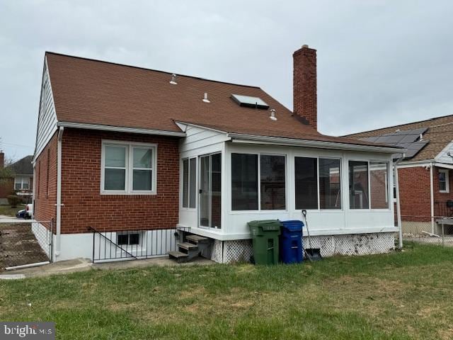 back of property with a lawn and a sunroom