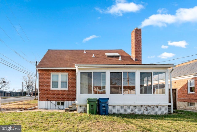 rear view of house featuring a sunroom and a lawn