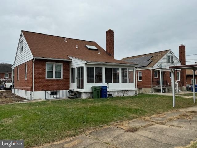 back of house featuring a sunroom and a lawn