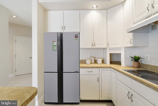 kitchen with tasteful backsplash, stainless steel fridge, and white cabinets