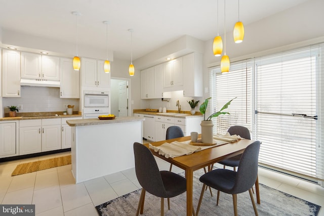 kitchen featuring hanging light fixtures, white cabinetry, a kitchen island, and white appliances