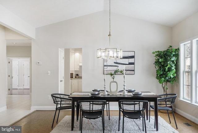 dining room with plenty of natural light, lofted ceiling, and an inviting chandelier