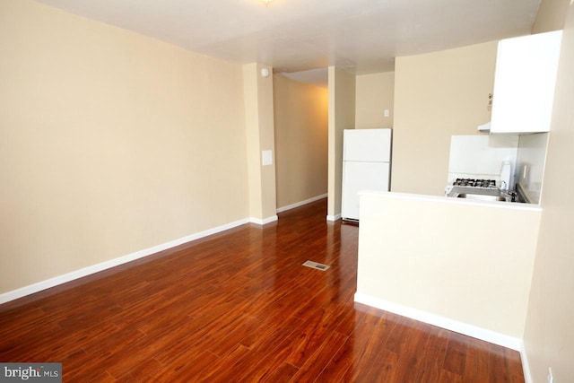 kitchen with white cabinets, dark hardwood / wood-style flooring, and white fridge