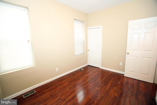 unfurnished bedroom with dark hardwood / wood-style flooring and multiple windows