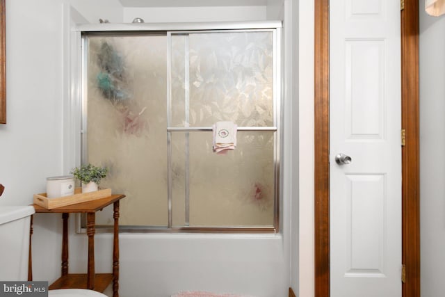 bathroom featuring bath / shower combo with glass door and toilet