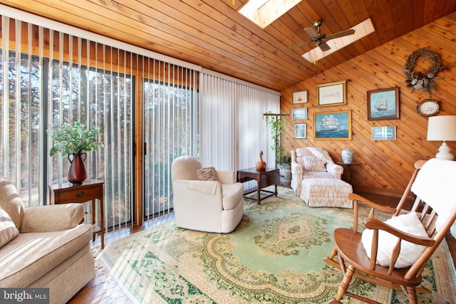 sitting room featuring vaulted ceiling with skylight, wood walls, and wood ceiling