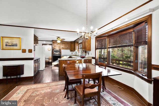 dining space with ceiling fan with notable chandelier, vaulted ceiling, and dark wood-type flooring