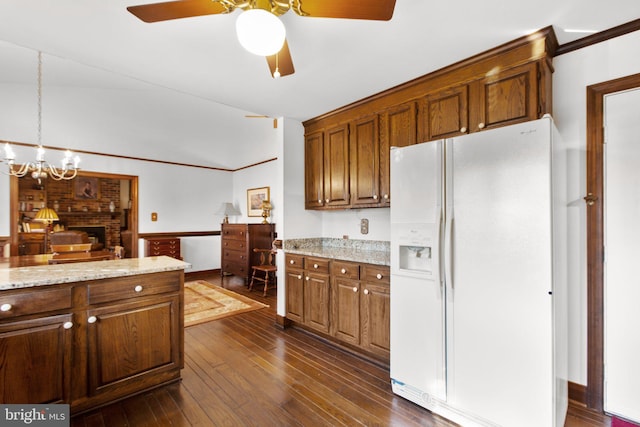 kitchen with light stone countertops, hanging light fixtures, dark hardwood / wood-style floors, white refrigerator with ice dispenser, and ceiling fan with notable chandelier