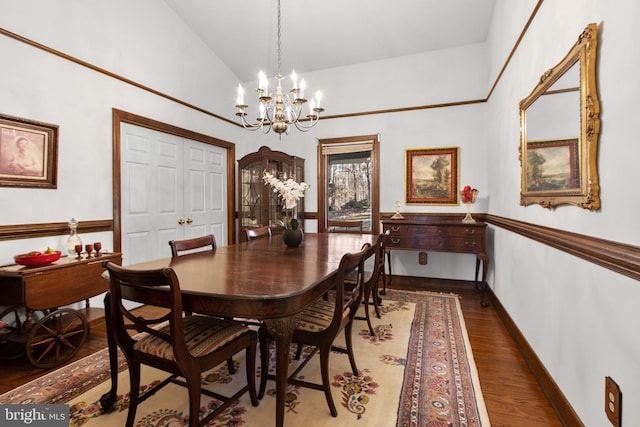 dining space with dark wood-type flooring, lofted ceiling, and a notable chandelier