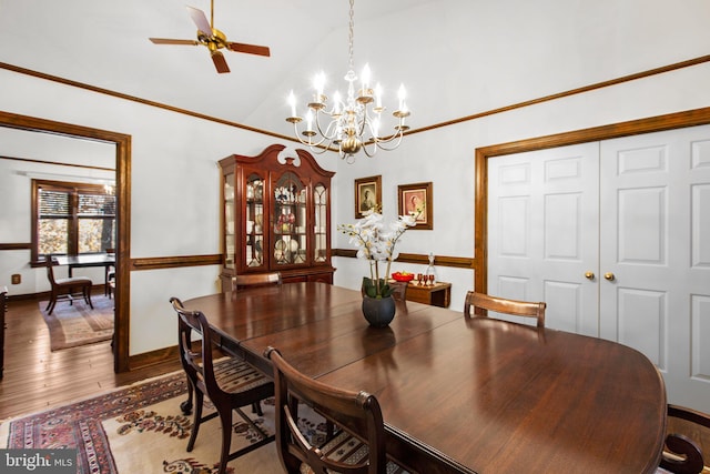 dining area with wood-type flooring, ceiling fan with notable chandelier, and vaulted ceiling