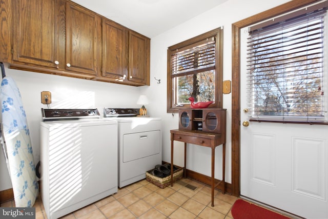 laundry area featuring washer and dryer, light tile patterned floors, and cabinets