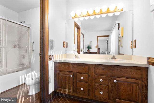 full bathroom featuring shower / bath combination with glass door, vanity, wood-type flooring, and toilet