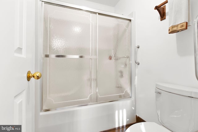 bathroom with toilet and shower / bath combination with glass door