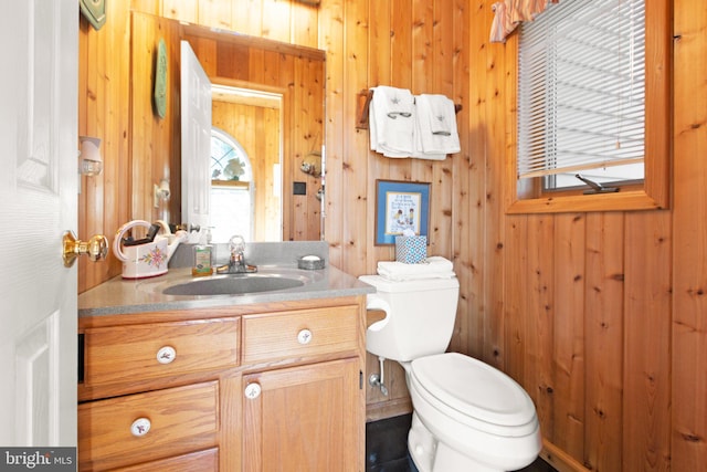 bathroom with wooden walls, vanity, and toilet