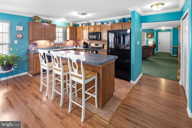 kitchen with a healthy amount of sunlight, a center island, black appliances, and light wood-type flooring