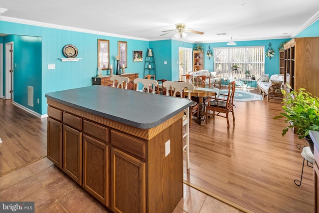 kitchen with crown molding, a kitchen island, and light hardwood / wood-style floors