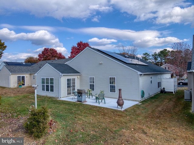 rear view of property featuring a yard, cooling unit, a patio, and solar panels