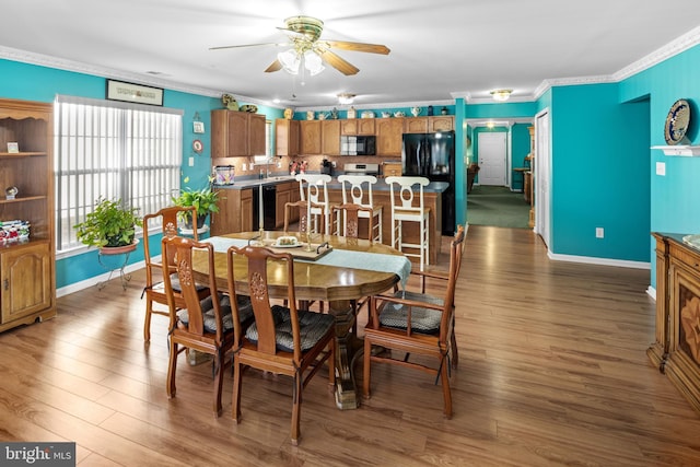 dining space with dark hardwood / wood-style flooring, ceiling fan, crown molding, and sink