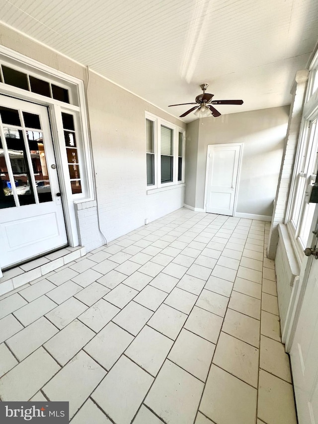 unfurnished sunroom featuring ceiling fan