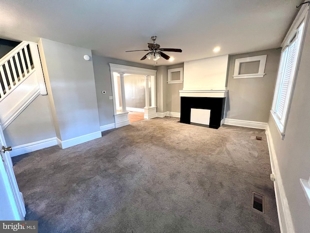 unfurnished living room featuring carpet floors, ornate columns, and ceiling fan