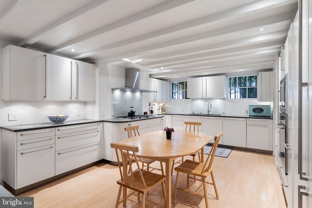 kitchen featuring appliances with stainless steel finishes, wall chimney exhaust hood, and white cabinetry