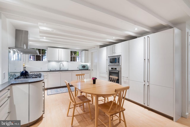 kitchen with stainless steel appliances, island range hood, white cabinetry, and beam ceiling