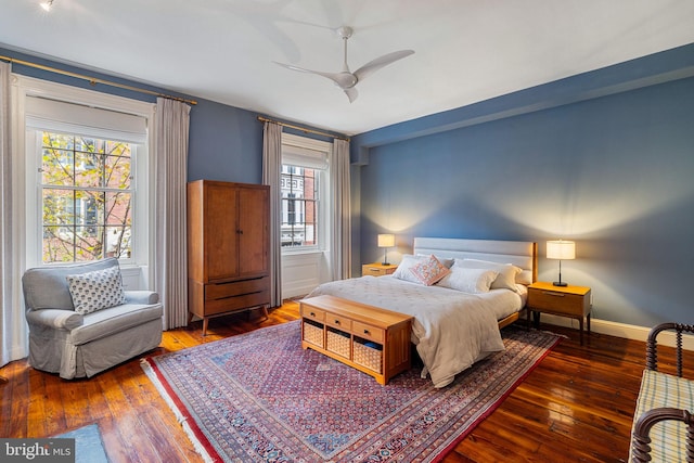 bedroom featuring ceiling fan, multiple windows, and dark hardwood / wood-style floors