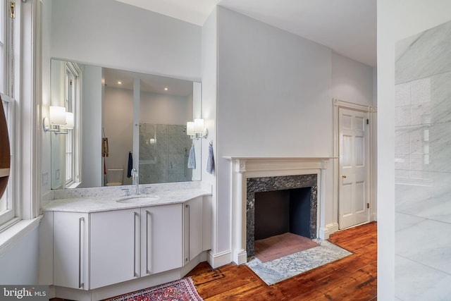 bathroom featuring a high end fireplace, a shower, wood-type flooring, and vanity