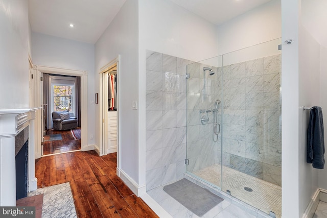 bathroom featuring a shower with door, a fireplace, and hardwood / wood-style flooring