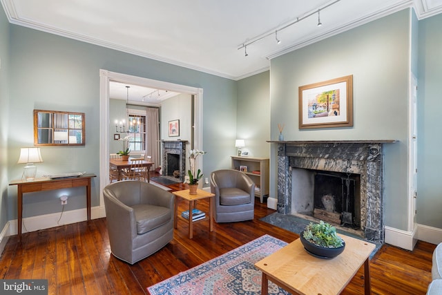 living area featuring a chandelier, a premium fireplace, track lighting, ornamental molding, and dark wood-type flooring