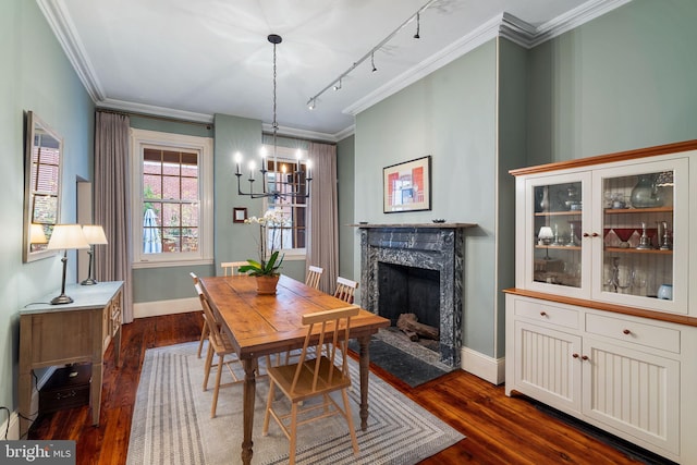 dining space with dark hardwood / wood-style floors, track lighting, an inviting chandelier, a high end fireplace, and ornamental molding