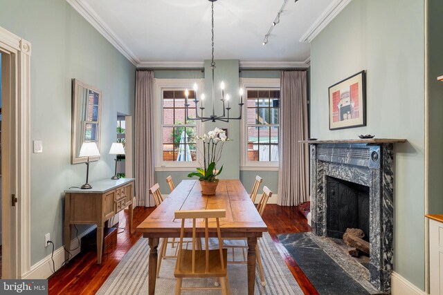 dining space with ornamental molding, a premium fireplace, track lighting, and dark hardwood / wood-style flooring