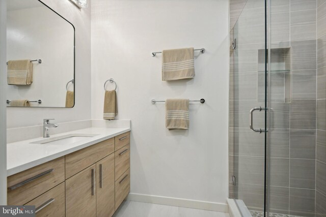 bathroom featuring tile patterned flooring, vanity, and a shower with shower door