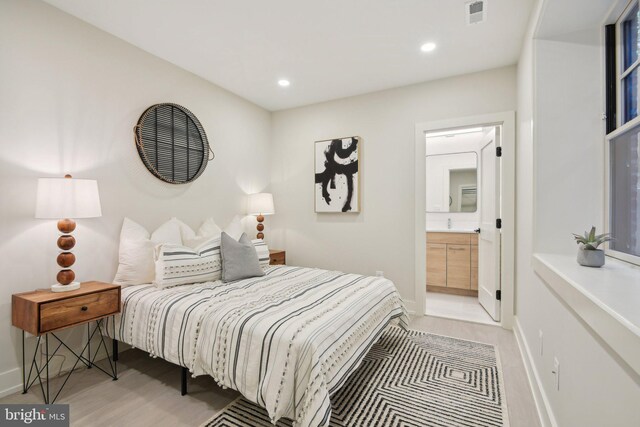 bedroom with ensuite bath and light hardwood / wood-style floors