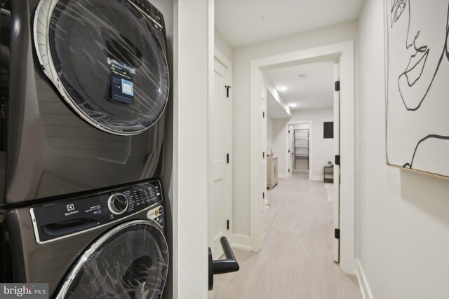 laundry area featuring stacked washer / dryer and light wood-type flooring