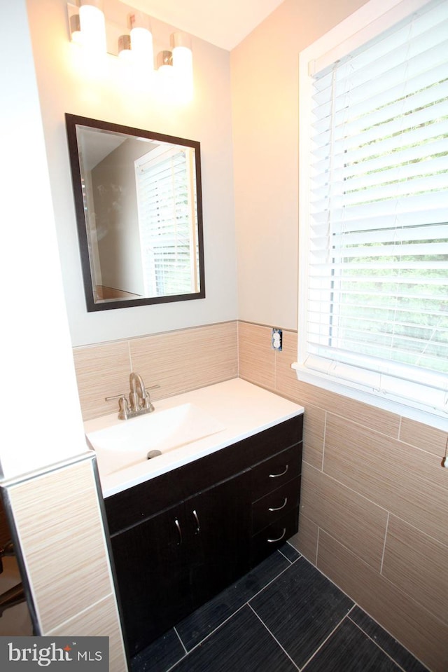 bathroom with tile patterned floors, plenty of natural light, vanity, and tile walls