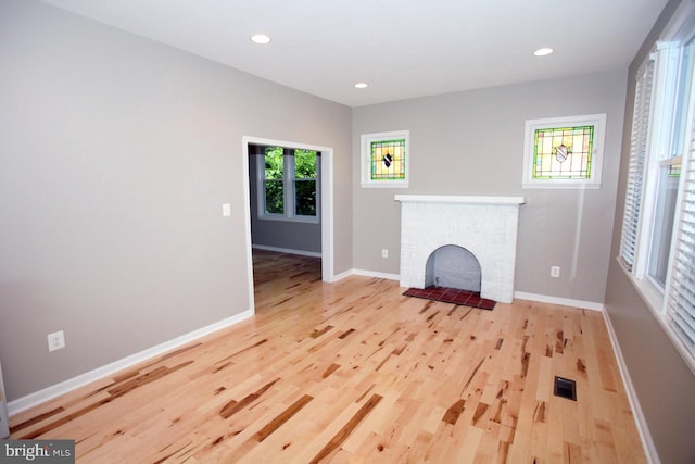 unfurnished living room featuring a fireplace and light hardwood / wood-style floors