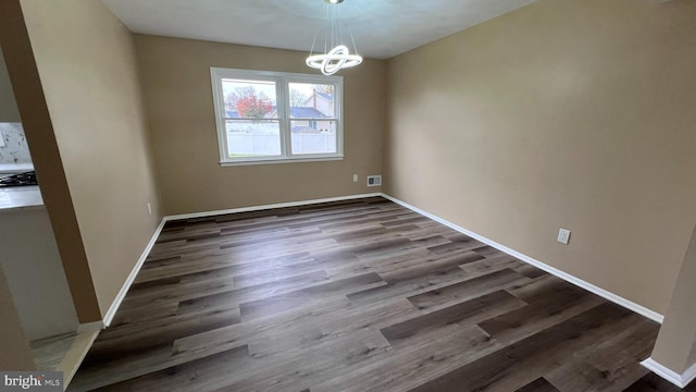 unfurnished dining area featuring dark hardwood / wood-style floors and an inviting chandelier