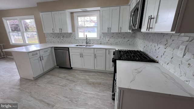 kitchen featuring white cabinets, appliances with stainless steel finishes, kitchen peninsula, and sink