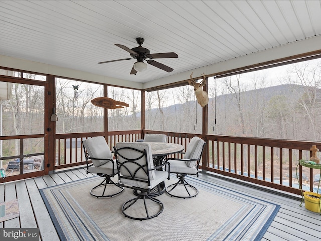 sunroom / solarium featuring a mountain view, ceiling fan, and wooden ceiling