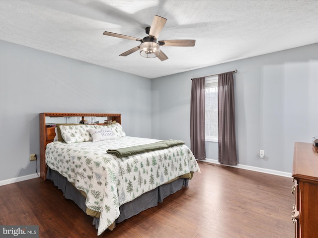 bedroom featuring dark hardwood / wood-style floors, ceiling fan, and a textured ceiling