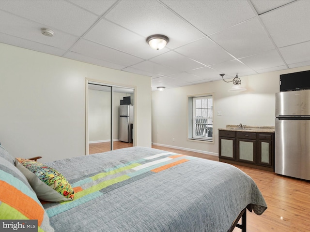 bedroom featuring stainless steel refrigerator, sink, a closet, and light wood-type flooring