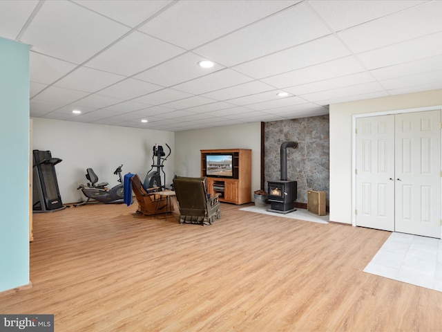 living area featuring a drop ceiling, light wood-type flooring, and a wood stove