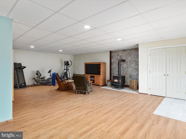 interior space with light wood-type flooring, a wood stove, and a drop ceiling