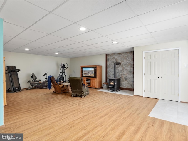 sitting room with a drop ceiling, light hardwood / wood-style floors, and a wood stove