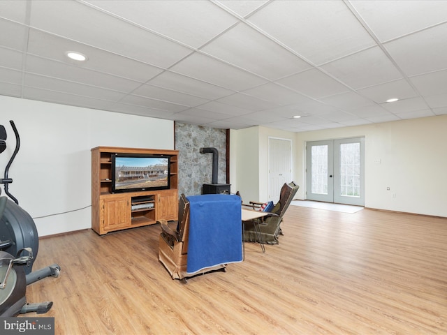 living room with a drop ceiling, light wood-type flooring, and french doors