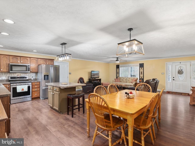 dining area with a textured ceiling, dark hardwood / wood-style flooring, ceiling fan, and crown molding