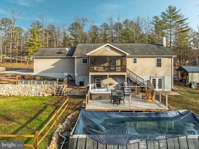 rear view of property featuring a swimming pool with hot tub, a yard, and french doors