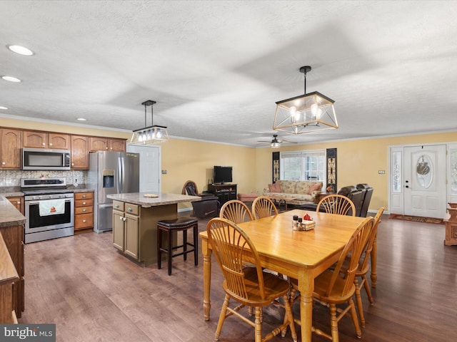 dining space featuring ceiling fan, dark hardwood / wood-style flooring, a textured ceiling, and ornamental molding