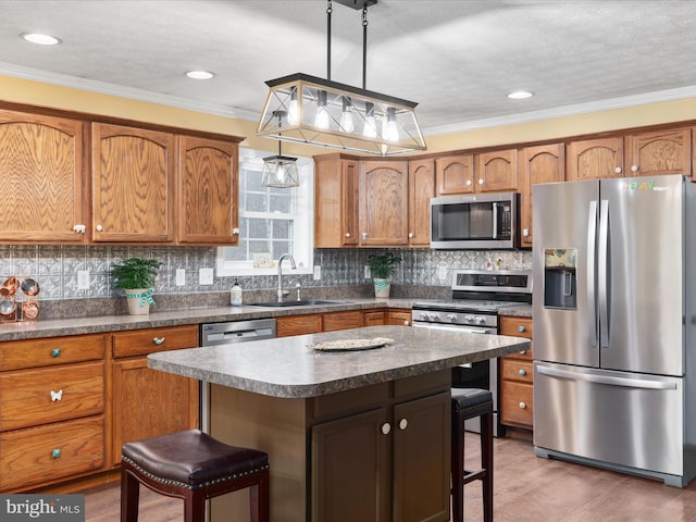 kitchen featuring a breakfast bar, stainless steel appliances, sink, a center island, and hanging light fixtures